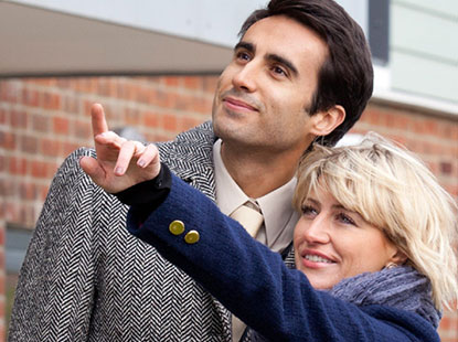 Two people looking at a house whilst one of them points