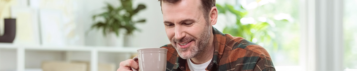 A person holding a mug and looking down smiling