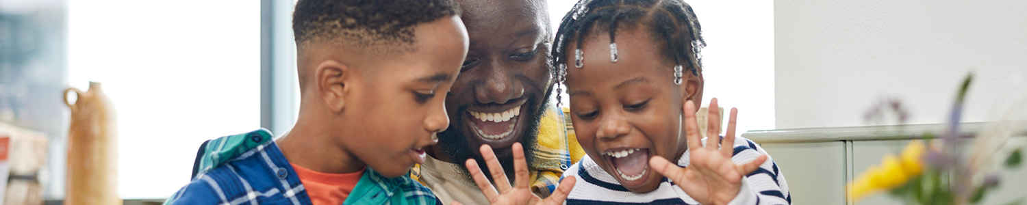 A person and two children smiling looking down at something