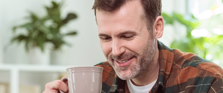 A person holding a mug and looking down smiling