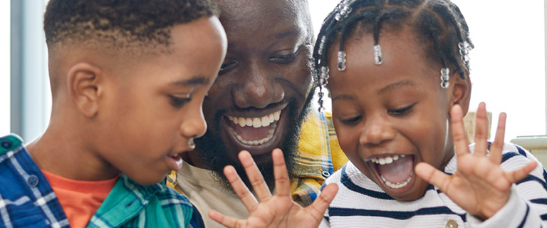 A person and two children smiling looking down at something