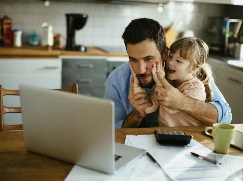 Little girl interrupts Dad using laptop in kitchen